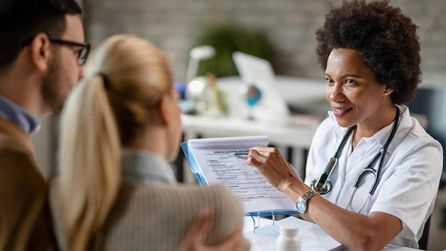 Doctor explaining consent obtainment to couple in practice