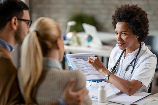 Doctor explaining consent obtainment to couple in practice