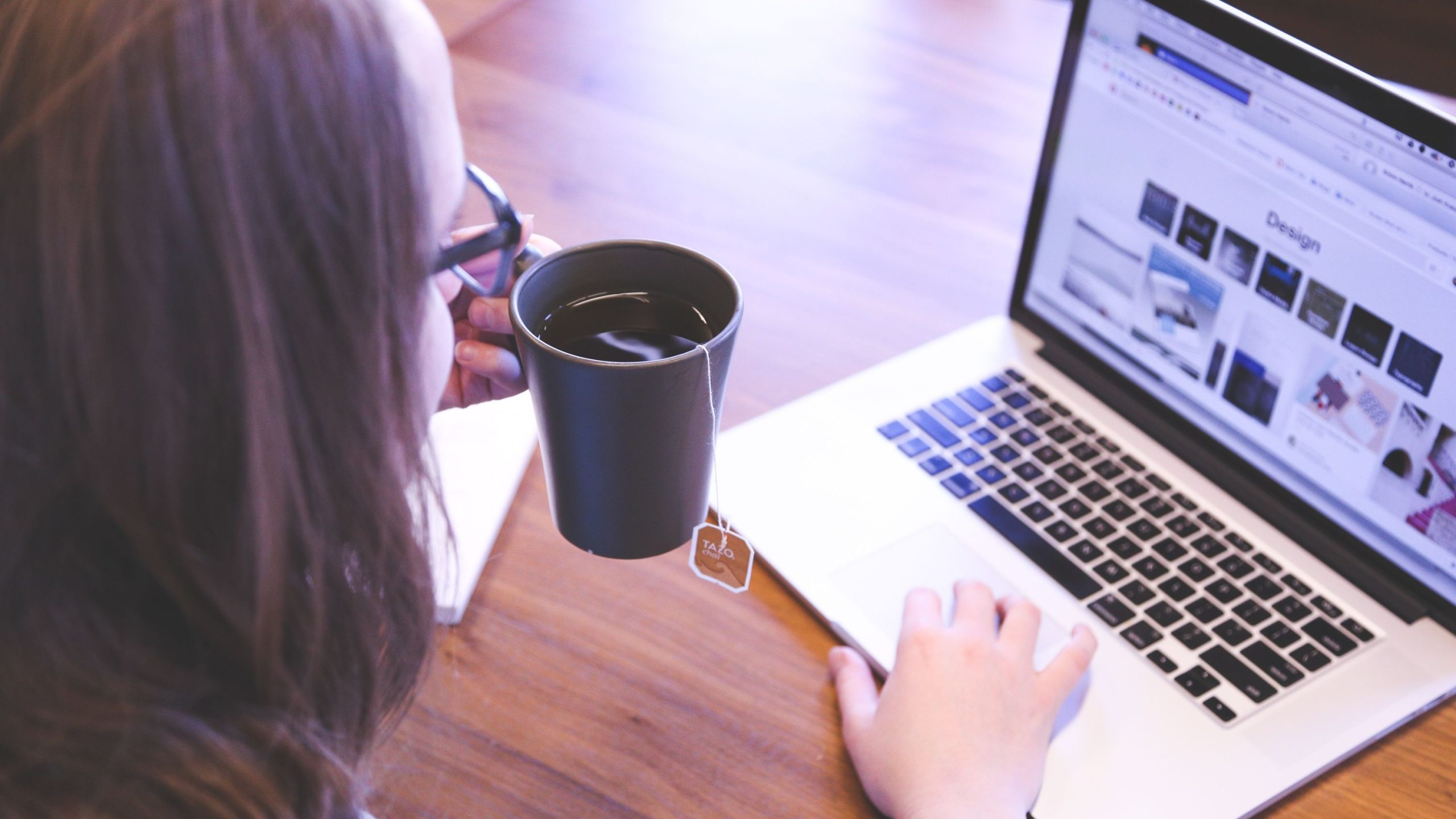 A woman holding cup while using a laptop